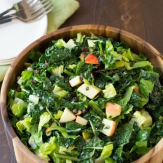 kale salad with apples in a wooden salad bowl