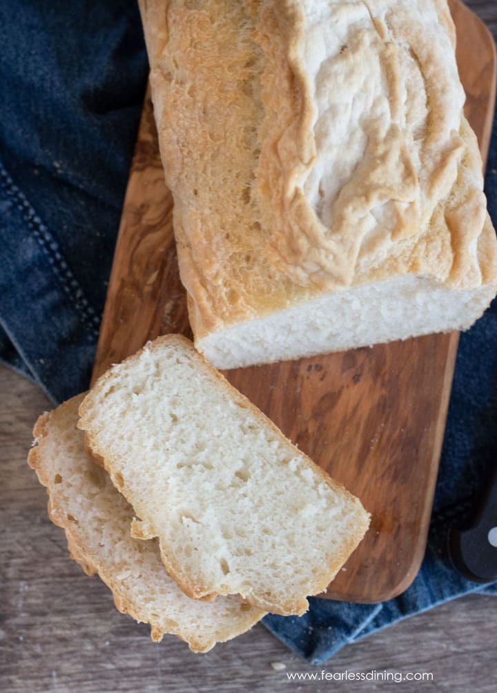 A sliced loaf of gluten free sourdough bread on a wooden cutting board.