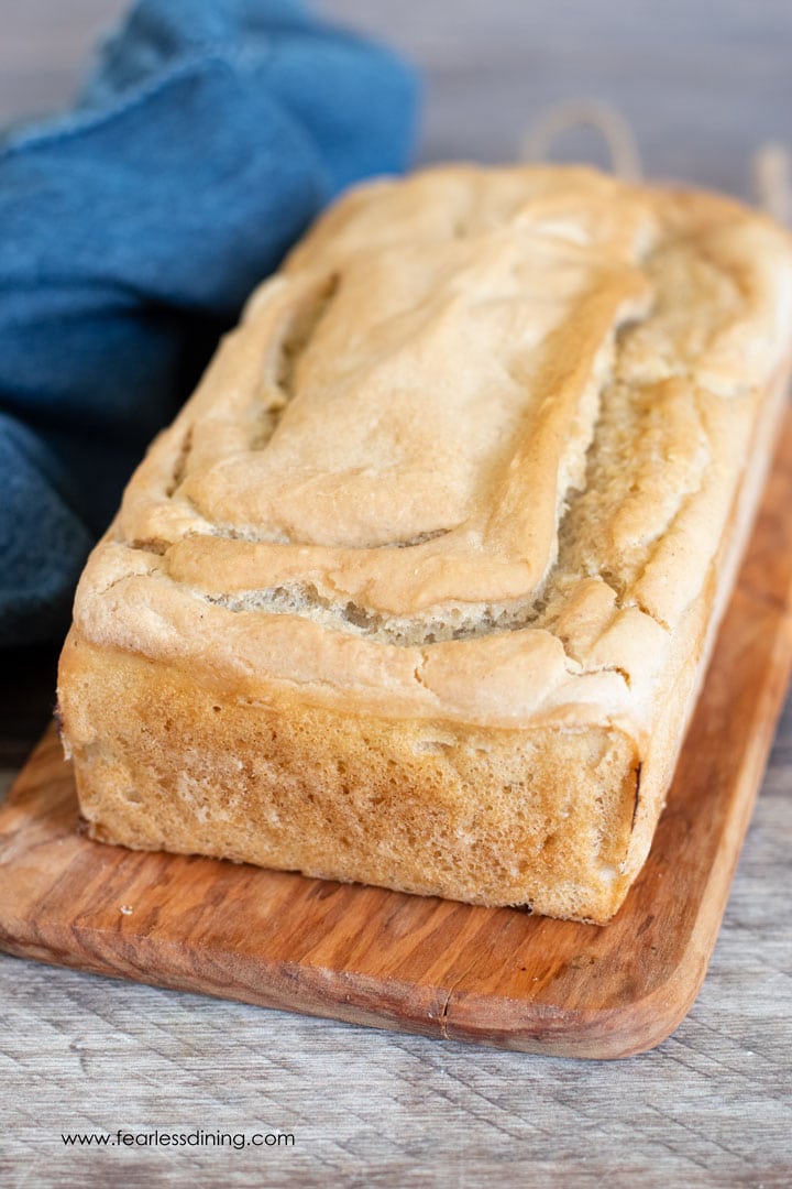 A loaf of baked gluten free sourdough bread on a cutting board.
