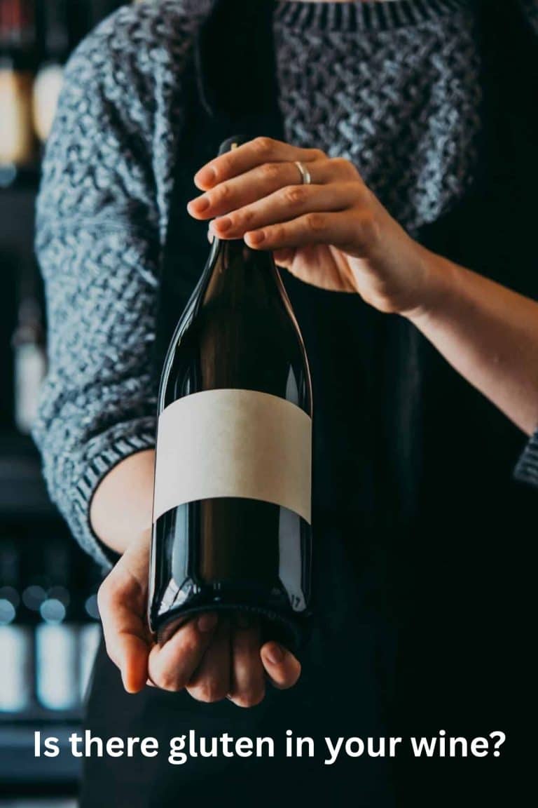 Holding up a red wine bottle.