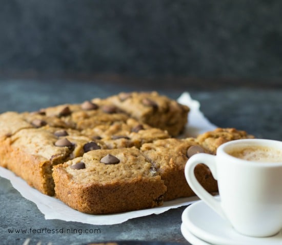 Banana bars on a paper towel. The sliced bars are next to a cup of espresso.