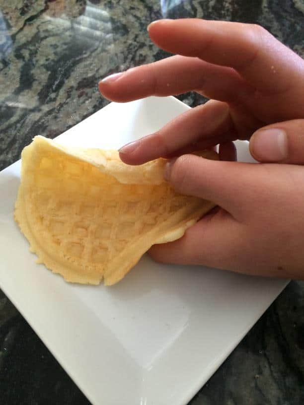 Rolling a gluten free waffle into a cone shape.