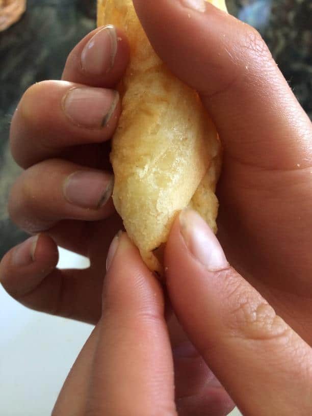 Pinching the bottom of a homemade gluten free waffle cone closed.