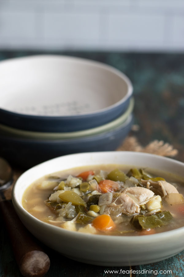 A bowl of soup on the counter next to a stack of three bowls.