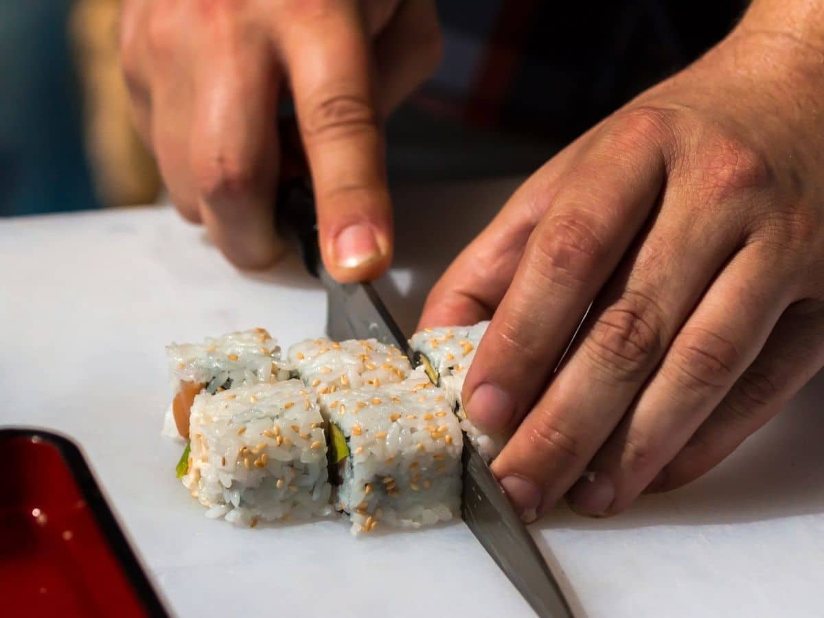 Cutting a sushi roll with a large knife.