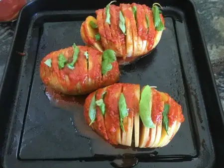 Hassleback potatoes with pizza sauce and basil in the layers