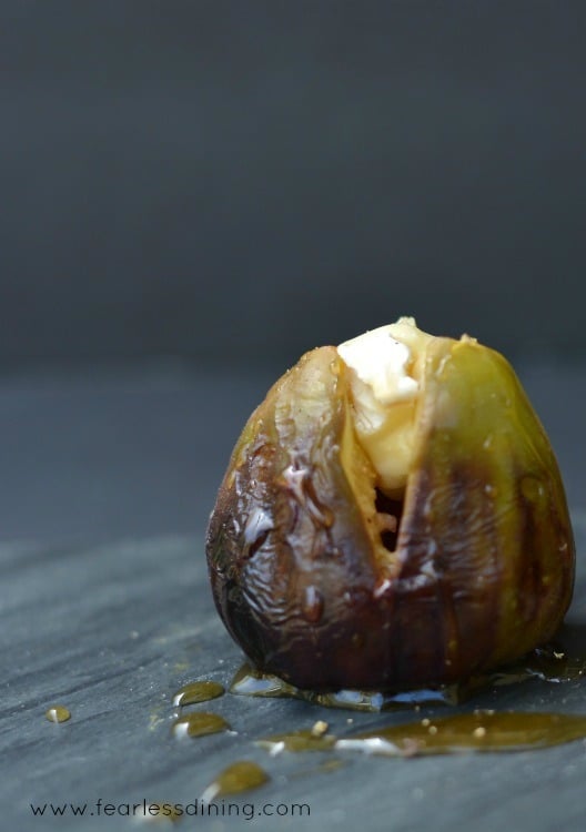 Single Grilled Brie Stuffed Fig with honey drizzled on top.