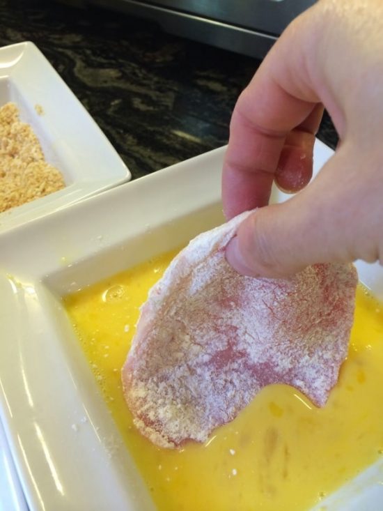 Dipping the pork cutlet into egg.