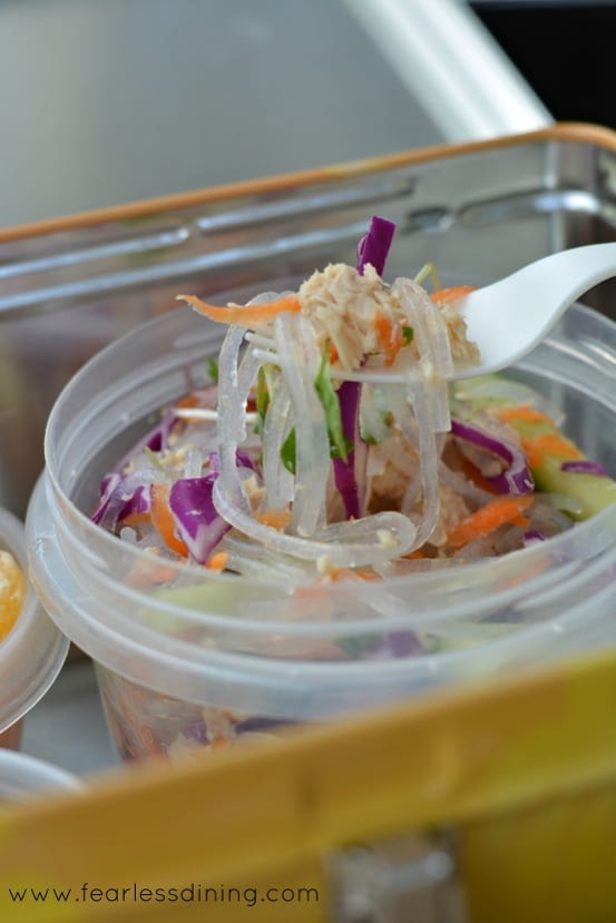 Chilled Tuna Noodle Salad in a plastic container with a fork dipping in.