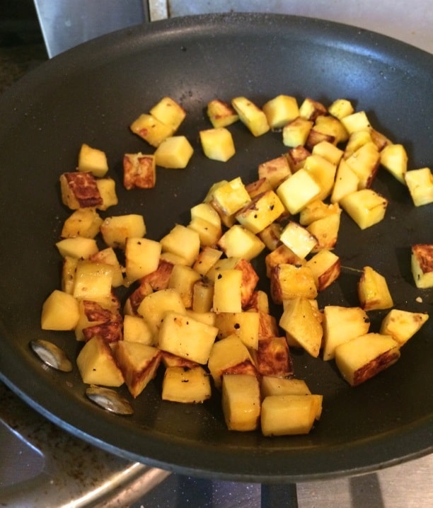 Cubbed delicata squash roasting in a skillet.