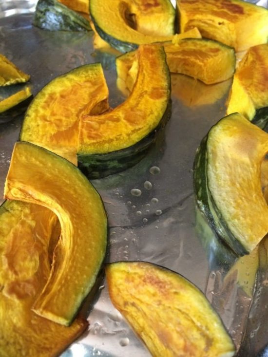 Roasted kabocha squash pieces on a baking sheet.