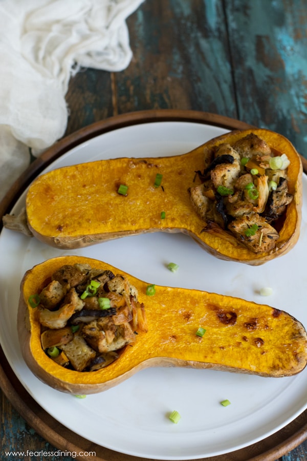 Two halves of a roasted butternut squash with stuffing in them.