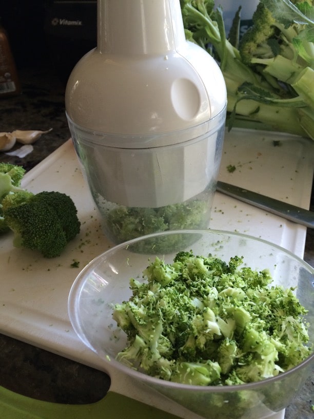 Chopping broccoli with a mini food chopper. The broccoli is in a bowl.