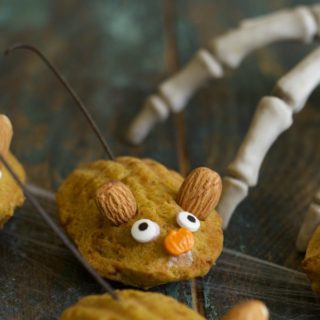 A close up of a gluten free pumpkin madeleine decorated with googly eyes and almond mouse ears.