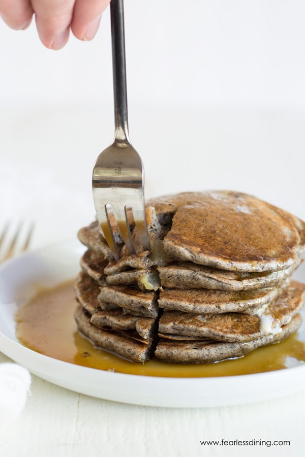 A fork cutting into a stack of buckwheat pancakes.