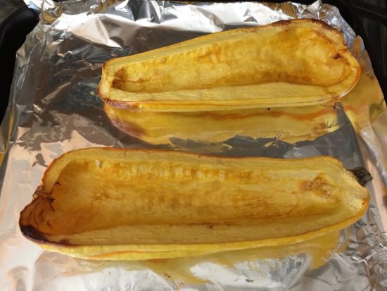 Roasted delicata squash halves on a baking pan.