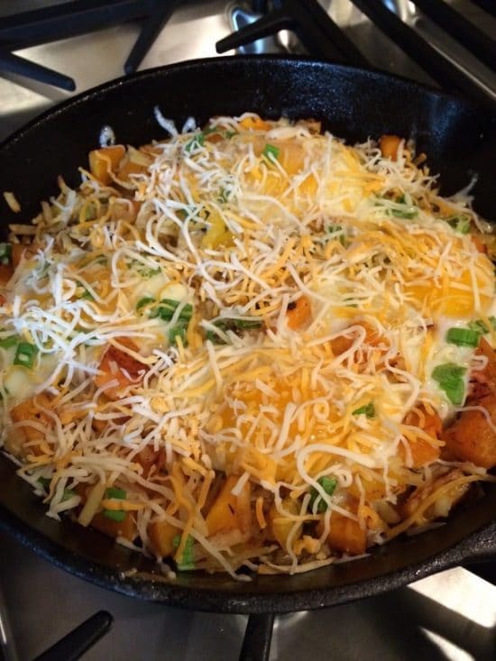 Adding cheese to breakfast skillet.