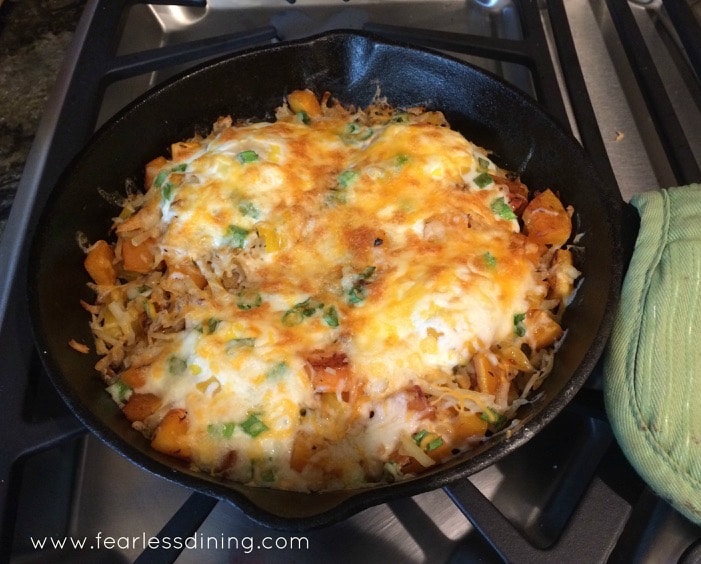 Butternut Squash Breakfast Skillet on the stove with a green pot holder around the handle.