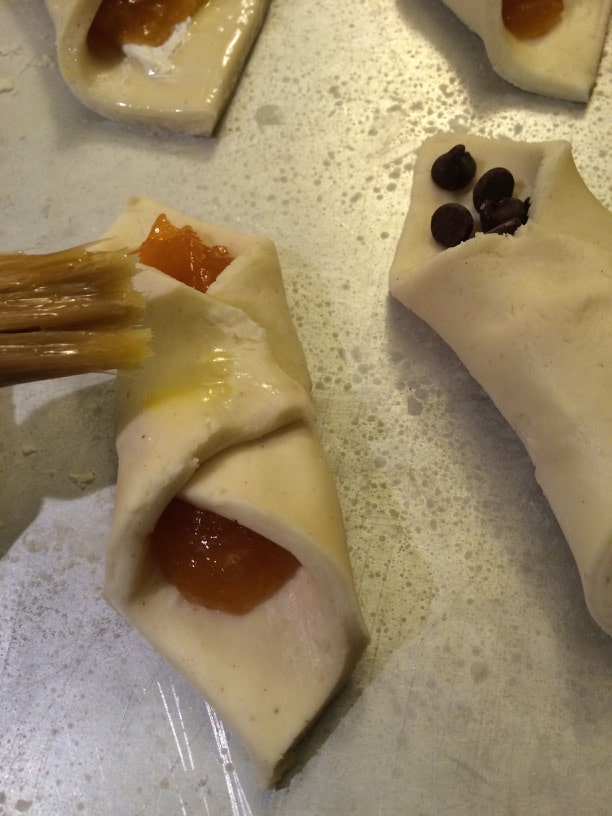 brushing egg wash onto pastry dough