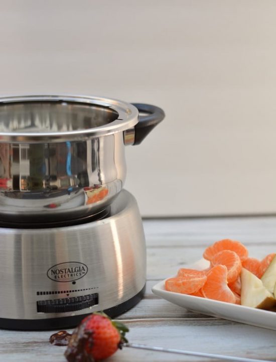 The fondue pot next to chopped fruits.