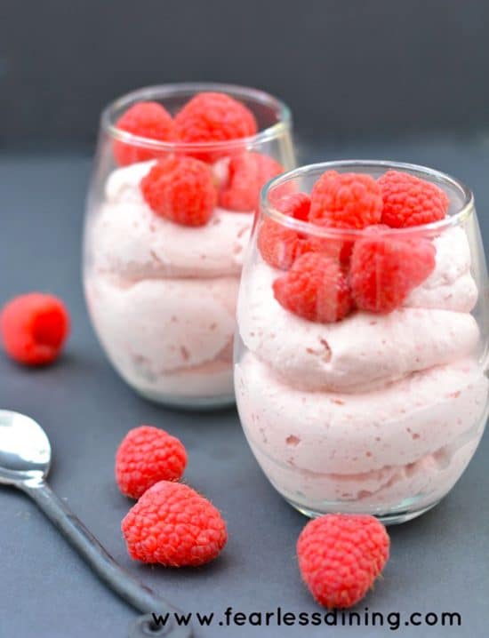Two glasses of fresh raspberry mousse. They are garnished with fresh raspberries.