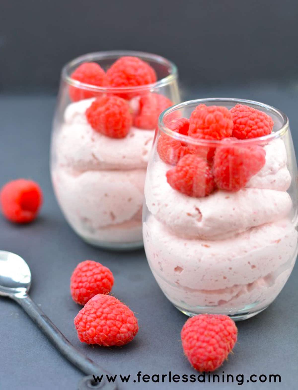 Two glasses of raspberry mousse topped with fresh raspberries.