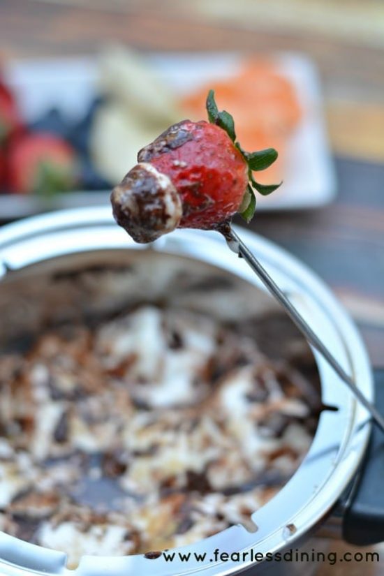 A strawberry with melted chocolate on a fondue fork.