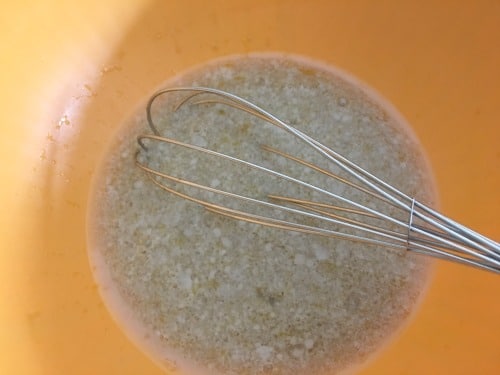 Wet ingredients in a bowl with a whisk blending it.