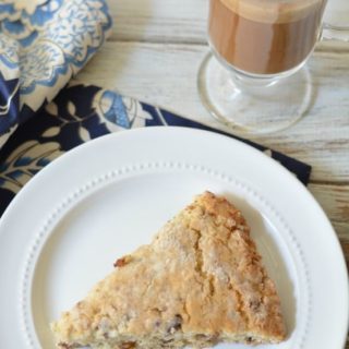 The top view of a date scones on a plate next to a glass mug of coffee.