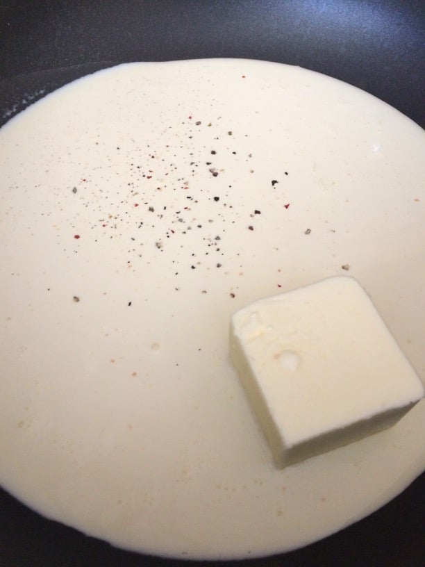 Heavy cream, salt, pepper, and butter in a skillet.