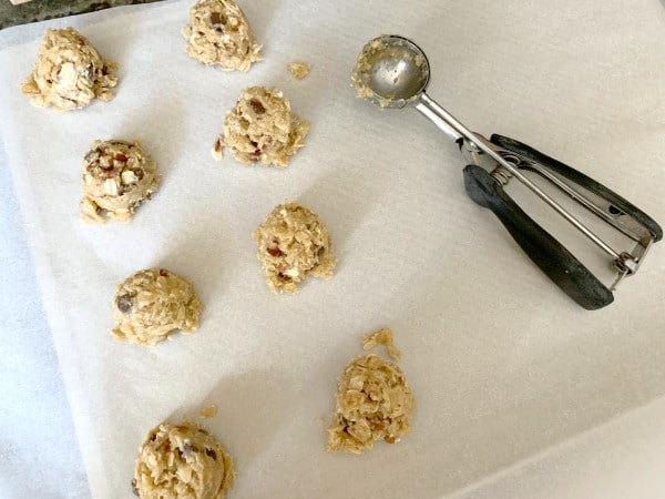 Using a cookie scoop to drop cookies onto a cookie sheet.