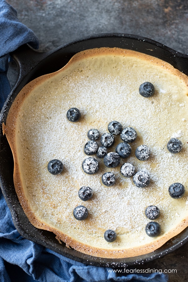 a top view of a gluten free dutch baby pancake topped with blueberries and powdered sugar