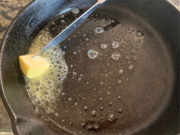 adding a little butter to a hot cast iron pan