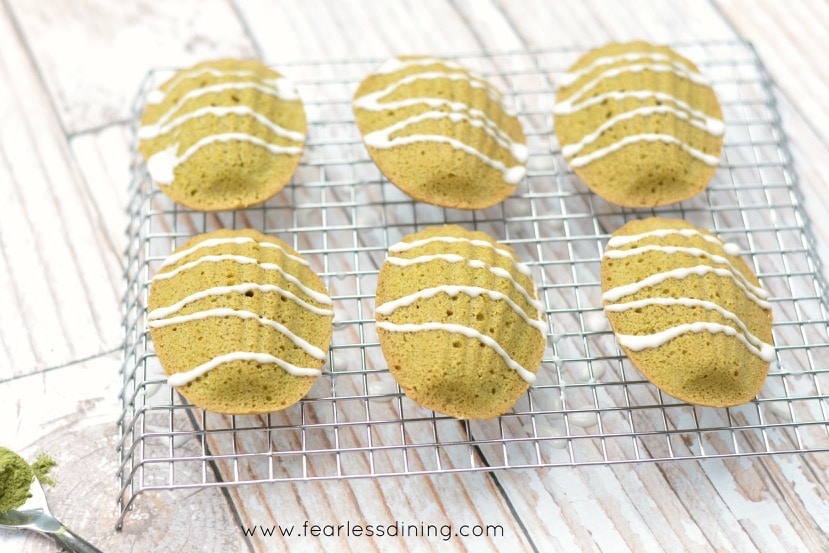 Horizontal picture of six Gluten Free Matcha Madeleines on a cooling rack.