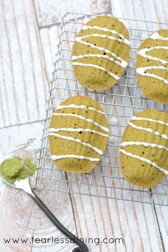 Gluten Free Matcha Madeleines on a cooling rack with icing drizzled on top of the cookies.