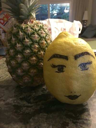A photo of one of our tree's big lemons next to a pineapple.