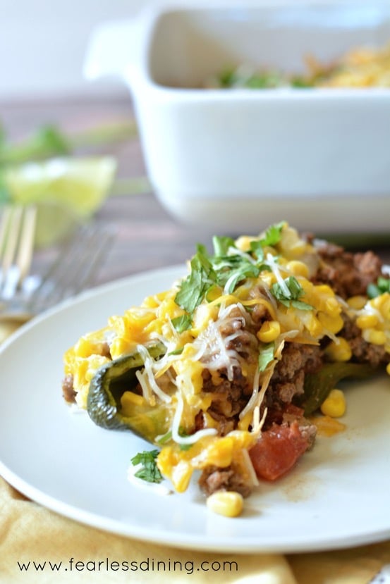 A stuffed pepper on a plate next to the casserole dish.