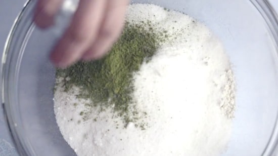 Adding matcha green tea powder to the dry ingredients.