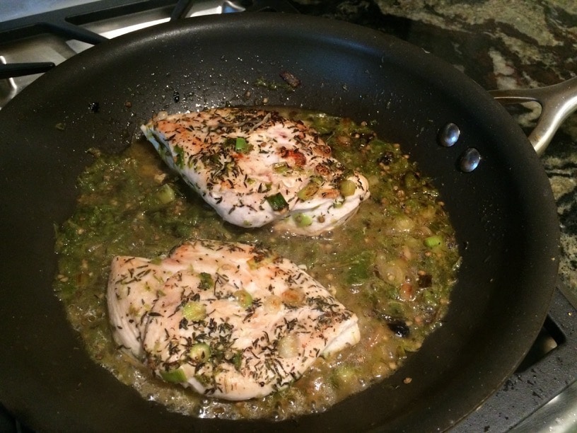 Chicken breasts in a frying pan saute in shishito sauce.