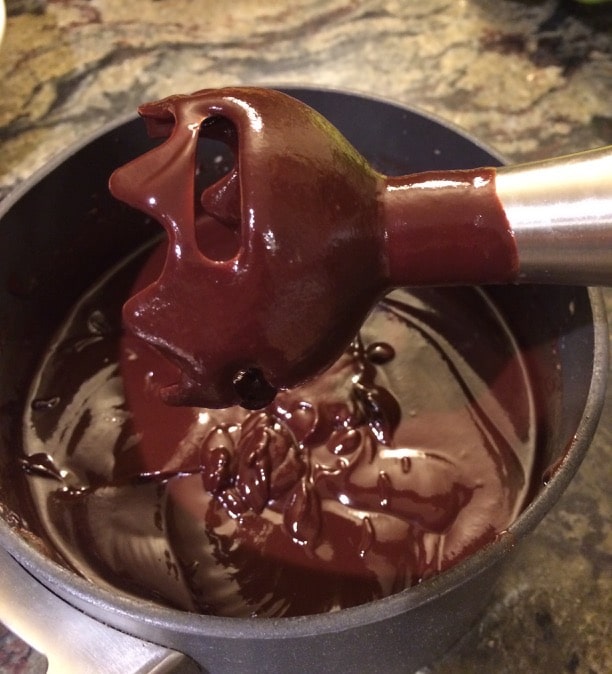 Melted chocolate dripping off an immersion blender.