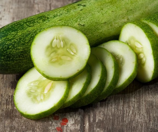 Cucumbers sliced on a wooden cutting board.