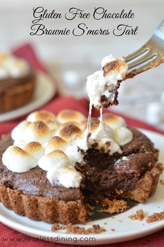 Gluten Free Chocolate Brownie S'Mores Tart with a fork taking out a piece. Melted marshmallow hangs from the fork
