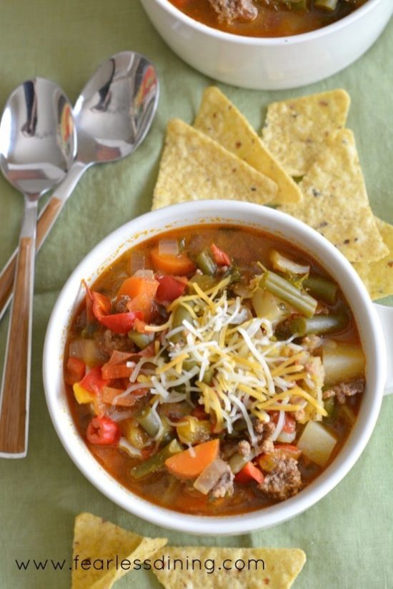 Country Hamburger Vegetable Soup in a large white mug with corn chips around the bowl