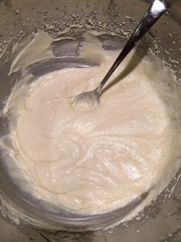 Apple cake batter in a bowl. A spoon is sitting in the batter after stirring.