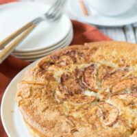 un-sliced gluten free apple cake on a white cake plate