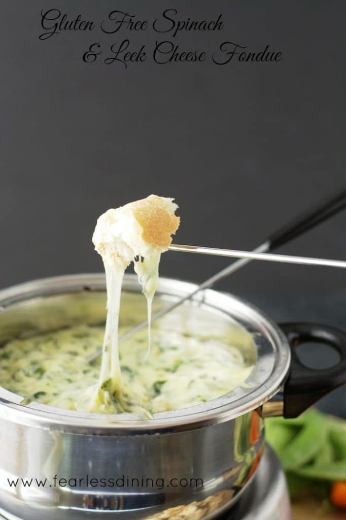 A piece of bread dipped into the Gluten Free Spinach and Leek Cheese Fondue 
