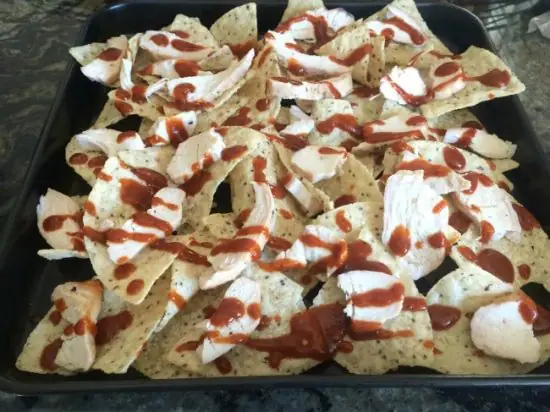 Tortilla chips with grilled chicken and barbecue sauce on top.