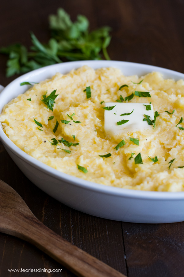 A casserole dish filled with mashed rutabagas. A melted square of butter is on top and parsley garnishes the dish