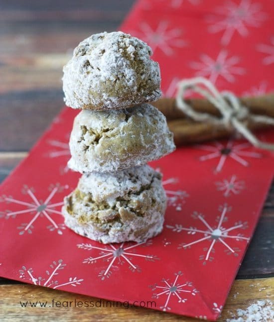 Three Gluten Free Pfeffernusse Cookies stacked on top of each other on top of a red gift bag.