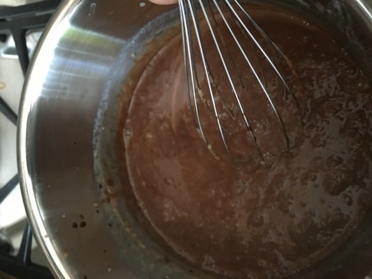 Cooking chocolate custard and stirring with a whisk